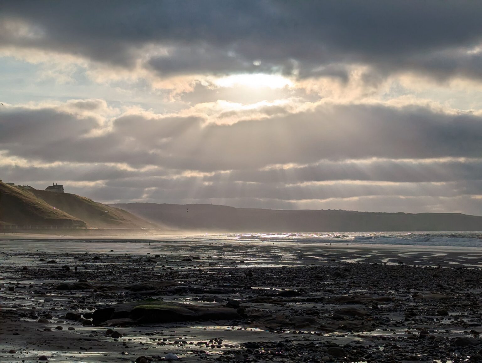 Sonnenuntergang über Whitby bei Ebbe mit warmem Licht und ruhiger Küstenlandschaft.